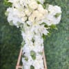 White floral wedding arrangement on an easel with lilies and roses