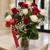 Red and white roses in a clear glass vase with a red polka-dot ribbon