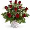 Red roses arranged with white baby's breath in a heart-patterned container