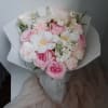 Pink and white bouquet of roses and small white flowers wrapped in paper