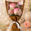 Bouquet of pink roses and white baby's breath wrapped in brown paper