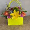 Bright mixed flower arrangement in a neon yellow gift bag