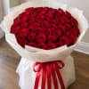 Large bouquet of red roses wrapped in white paper with a red ribbon