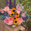 Colorful bouquet with sunflowers, pink roses, and purple blooms in a silver vase