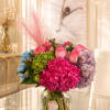 Colorful bouquet of hydrangeas and pink roses in a clear glass vase