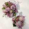 Two lavender rose corsages with pink filler flowers and white ribbon