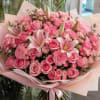 Large pink bouquet of roses, lilies, and carnations wrapped in pale paper