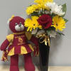 Bouquet of yellow and white daisies with a red rose in a black vase beside a teddy bear
