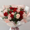 Bouquet of red and pale pink roses wrapped in white paper