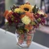 Mixed bouquet with a sunflower in a glass vase and plaid ribbon