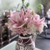 Pink lilies and roses arranged in a patterned vase
