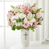 Pink and white flower arrangement in a white vase with a silver cross