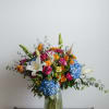 Colorful mixed bouquet in a green glass vase with lilies and hydrangeas