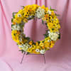 A bold circular sympathy wreath that greets the service with bright, uplifting