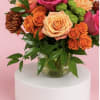 Bouquet of pink and peach roses with orange blooms in a glass vase