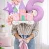 Person holding pastel castle and number 5 balloons with flower balloons