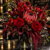 Red floral arrangement in a glass vase with a black ribbon