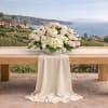 White and blush rose arrangement on a draped table outdoors