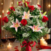 Bouquet of red roses and pink lilies in a glass vase with a red ribbon