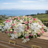 White and pink floral casket spray on a wooden casket