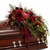 Deep red floral spray on a polished wooden casket
