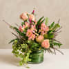 Pink roses and lilies in a glass vase with trailing ivy