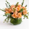 Peach roses and small pink flowers in a clear glass vase