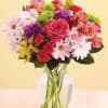 Mixed bouquet of pink roses, daisies, and carnations in a glass vase