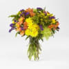 Mixed bouquet of yellow, orange, and purple flowers in a clear glass vase