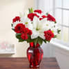 Red roses, white lilies, and white daisies in a red glass vase