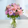 Pink lilies and purple daisies in a clear glass vase
