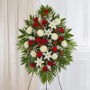 Standing floral spray with red and white flowers on a tripod easel