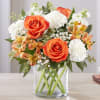 Orange roses and white carnations in a clear glass vase