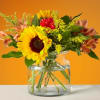 Sunflower and mixed flower bouquet in a clear glass vase