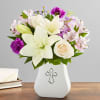 Bouquet of white lilies, roses, and purple flowers in a white vase with a cross