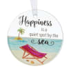 Round hanging ornament with beach chair art and the words 'Happiness is a quiet spot by the sea'.