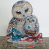 Jeweled owl and owlet figurine with blue gem cube and red beaded bow on a clear stand