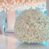 Large spherical arrangement of ivory and blush roses on a low white base in a modern lobby
