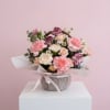 This petite floral basket showcases fresh mini carnations arranged with light filler