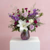 A mix of lavender and white roses, white lilies, and purple blooms