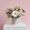 Soft pink and white blooms arranged in a keepsake floral mug. Ready