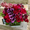 A deep colored modern arrangement with beautiful orchids, calla lilies and a