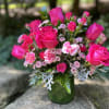 Pink roses and small pink flowers in a green glass vase