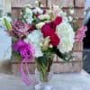Bouquet of pink roses, white hydrangeas, and lilies in a clear glass vase