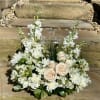 White floral arrangement with roses and a clear glass cross centerpiece