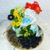 Floral arrangement with a white mermaid figurine, roses, and mixed blooms on a tray