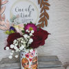 Bouquet of red roses and pink flowers in a printed gift cup