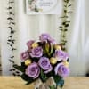 Lavender rose arrangement in a glass vase with gold-wrapped chocolates