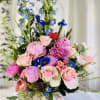 Pink roses and peonies arranged with blue irises in a white hat box