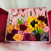 Gift box with pink MOM letters, roses, sunflowers, and chocolates